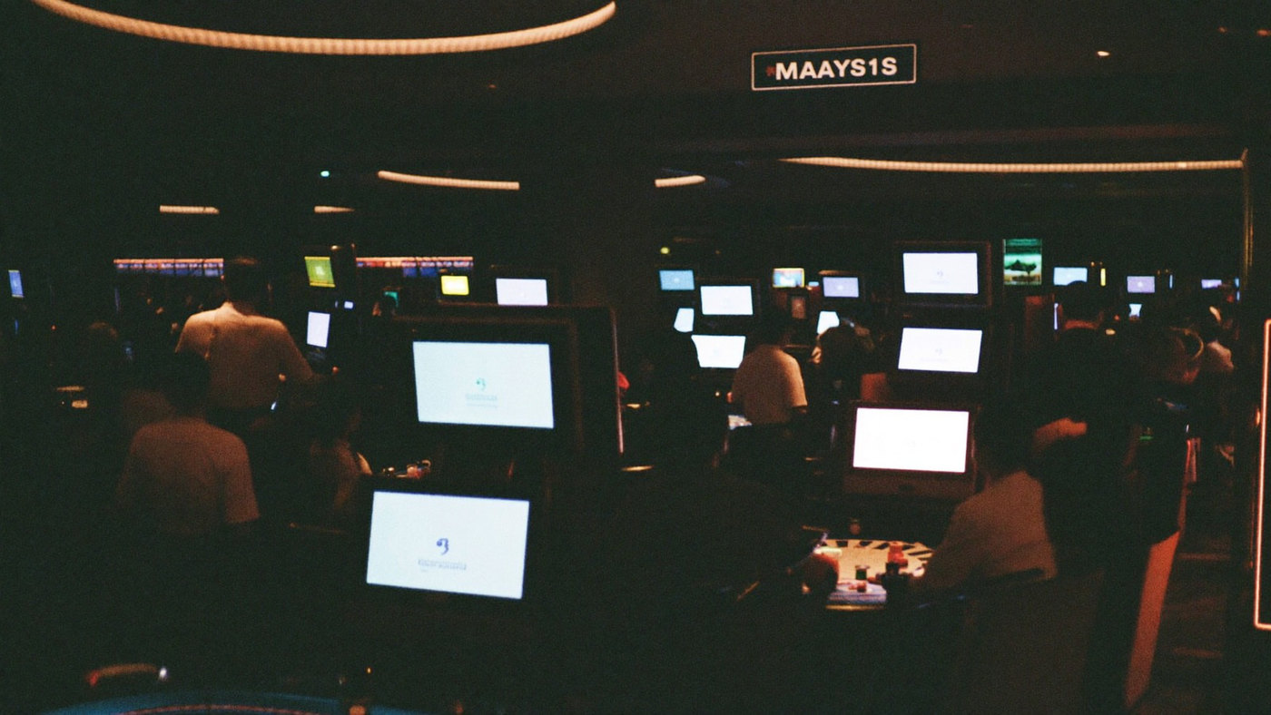 Wide view across a busy casino room of gaming tables and guests