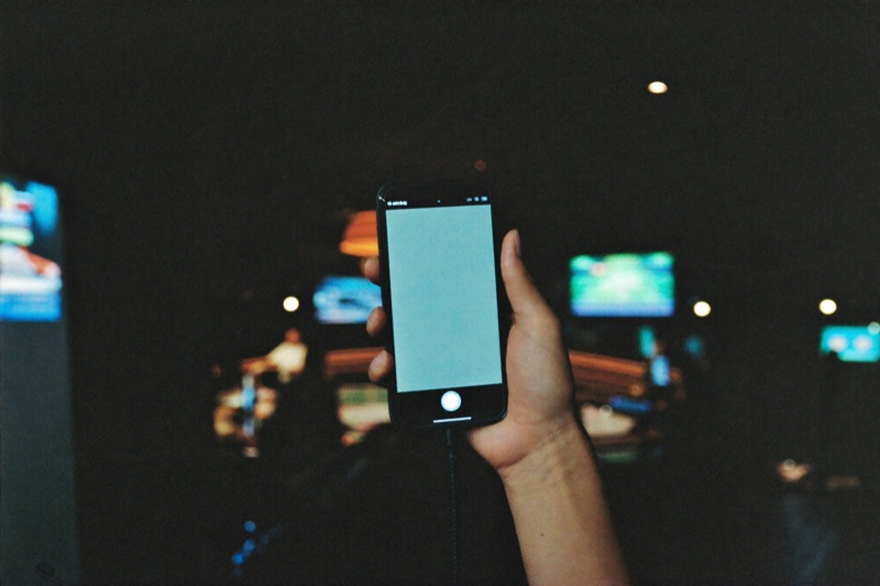 A phone held up in front of a busy casino room of tables and lights