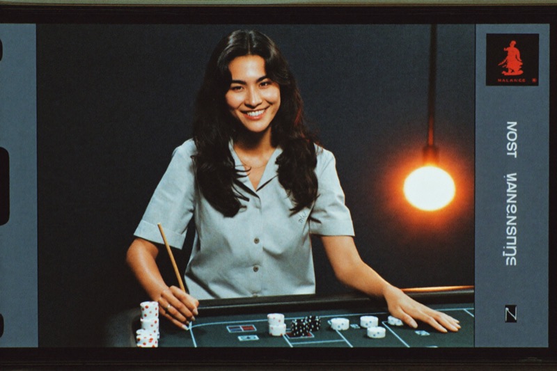 A live dealer at a baccarat table seen on a phone screen in portrait