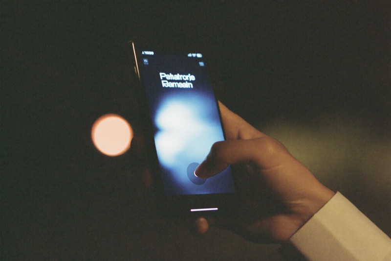 A thumb pressing a sign-in button on a phone at night