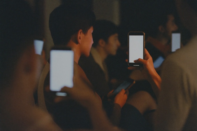 A group of friends in Kuala Lumpur watching sport with phones in hand
