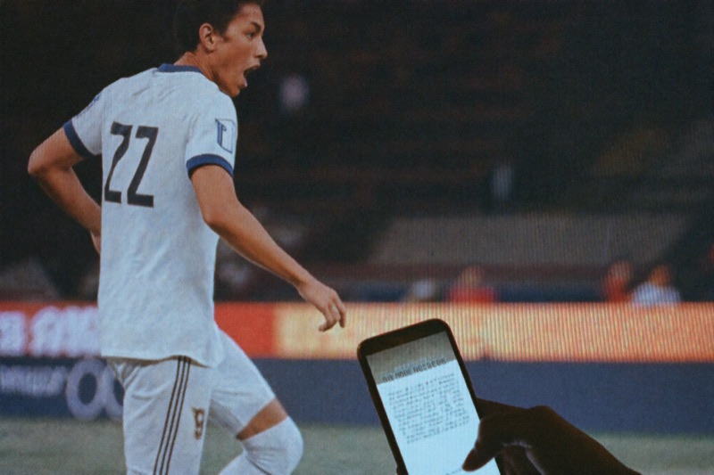 Perlawanan bola atas TV dengan bet slip terbuka atas phone